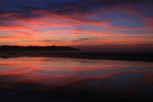 蓝红色和黄色落日的天空下的水体 · 免费素材图片