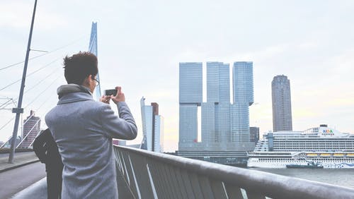 男子拍摄城市景观的后视图 · 免费素材图片