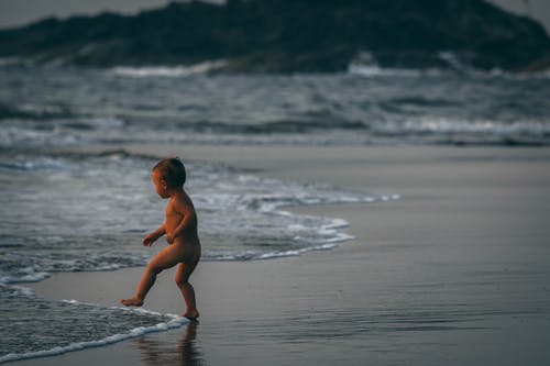 站在海边波浪旁边的男孩 · 免费素材图片