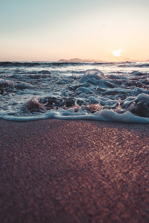 海浪在日落期间在海岸上崩溃 · 免费素材图片