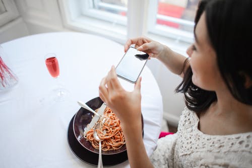 拍她的食物的照片的女人 · 免费素材图片