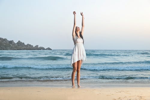 举手的白色无袖连衣裙的女人的照片 · 免费素材图片