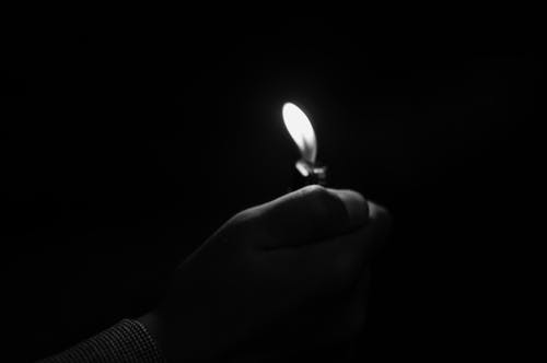在暗室里举蜡烛的手的特写镜头 · 免费素材图片