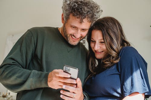 在房子的房间里作物微笑夫妇看智能手机 · 免费素材图片