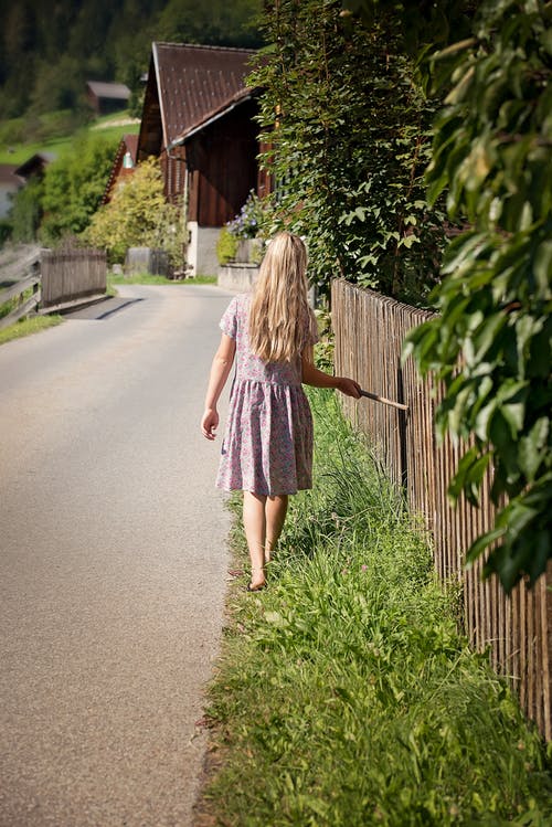 白天在绿色的草地上漫步的白色和紫色衣服的女孩 · 免费素材图片
