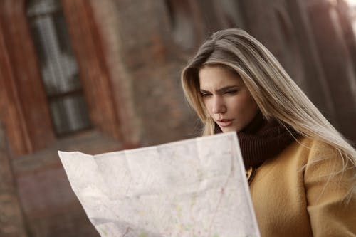 棕色长袖衬衫拿着地图的女人 · 免费素材图片
