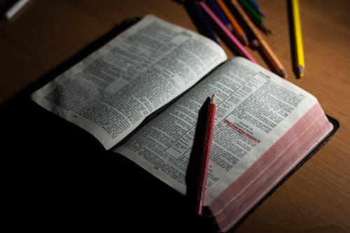 打开圣经页上的粉红色铅笔和粉红色 · 免费素材图片
