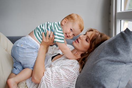 母亲带着快乐的小男孩在沙发上休息 · 免费素材图片
