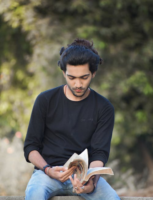 黑色长袖t恤阅读书中的男人 · 免费素材图片