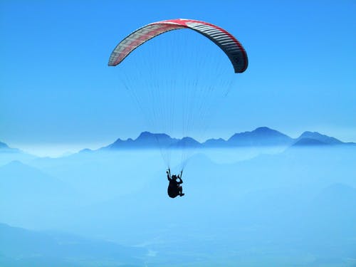 白天在云层上方做滑翔伞的人 · 免费素材图片