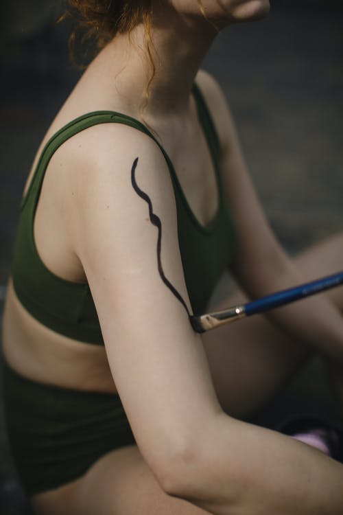 女人穿着绿色运动胸罩有人体彩绘 · 免费素材图片