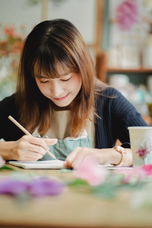 在笔记本的正面亚裔妇女文字在轻的屋子里 · 免费素材图片