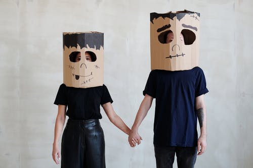 情侣牵着彼此的手戴着diy纸板盒面具 · 免费素材图片