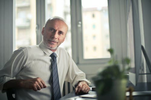 坐在桌子旁边的椅子上的男人 · 免费素材图片