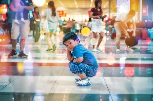 蹲在白色地板砖上的男孩 · 免费素材图片