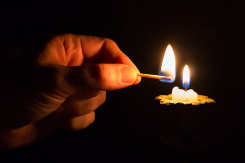 拿着火柴火在蜡烛着火的人 · 免费素材图片