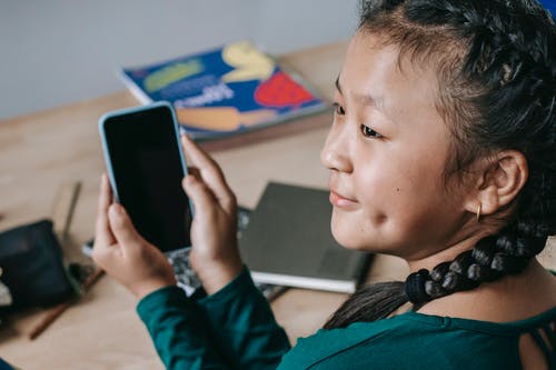 快乐的族裔孩子在学校使用手机 · 免费素材图片