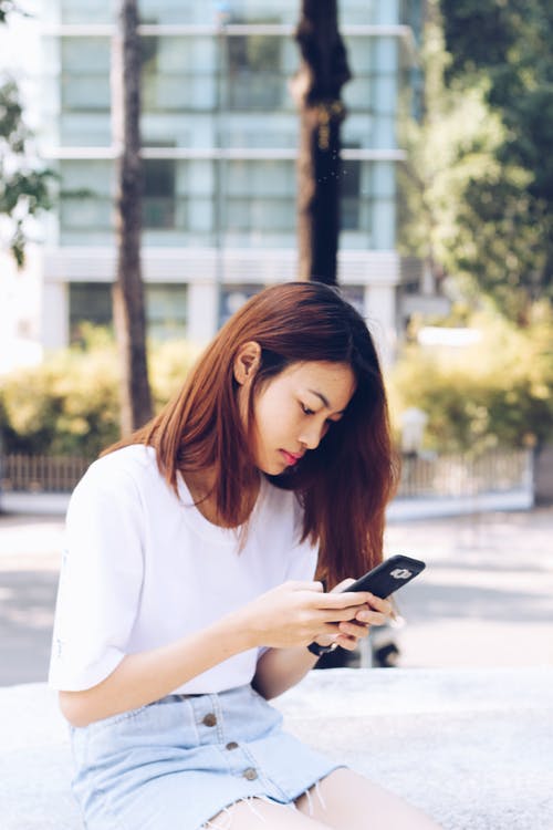 女人坐在焦点摄影上拿着电话 · 免费素材图片