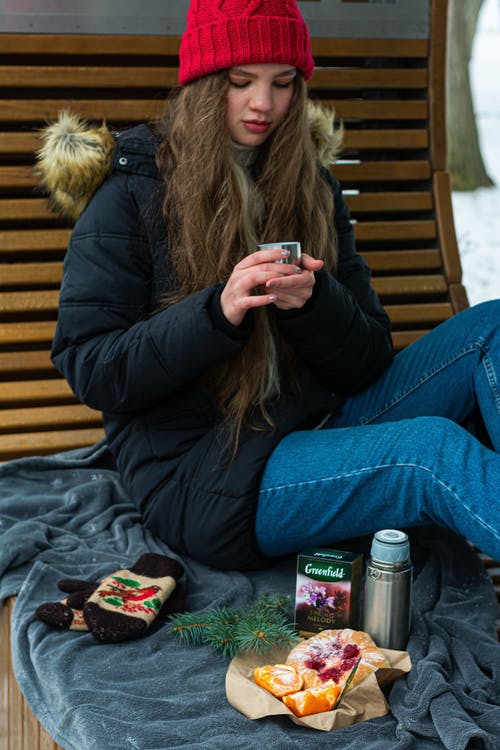 坐在长凳上的黑夹克的女人 · 免费素材图片