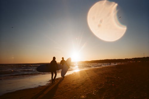 人们携带在海边散步的冲浪板 · 免费素材图片