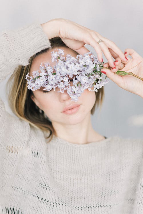 拿着白花花束的白色针织毛衫的女人 · 免费素材图片