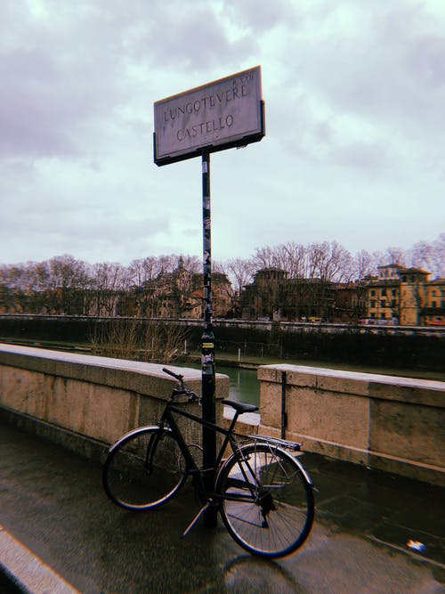 黑色城市自行车停在灰色混凝土墙旁边 · 免费素材图片