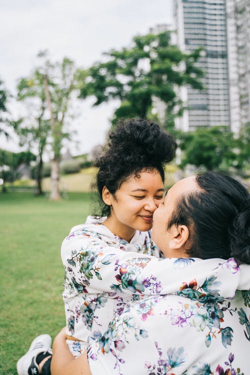 白色红色和绿色花衬衫的女人接吻黑头发的女人 · 免费素材图片