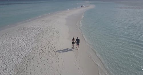 夫妻在拍摄与无人机的海滩上散步 · 免费素材视频
