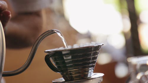 将热水倒在装有咖啡粉的便携式滤杯上 · 免费素材视频
