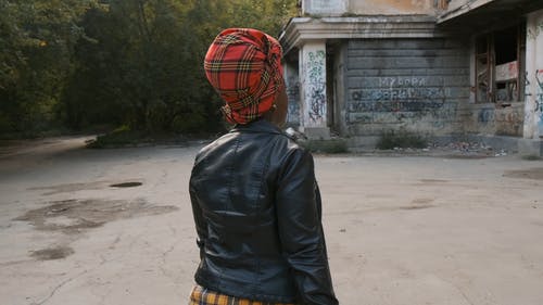 一个女人在皮夹克走在一个废弃的物业 · 免费素材视频