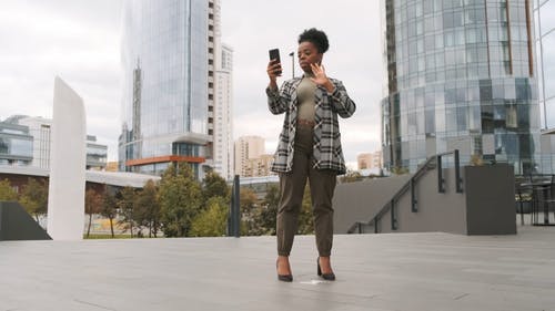 建筑物外面的手机上的视频通话的站立的女人 · 免费素材视频
