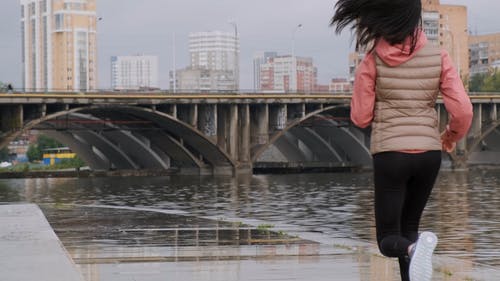 一个女人在河岸边的人行道上奔跑 · 免费素材视频
