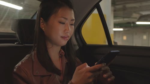 女人坐在一辆汽车的后面和使用她的电话 · 免费素材视频