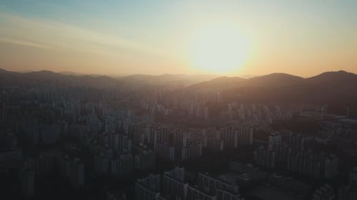 一个城市从山后冉冉升起的太阳中获取阳光 · 免费素材视频