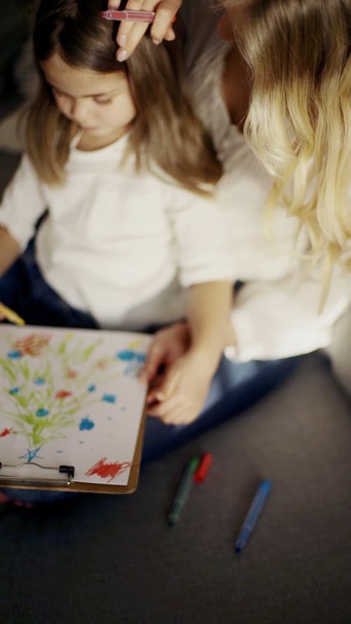 一位母亲看着女儿在纸上做艺术品 · 免费素材视频