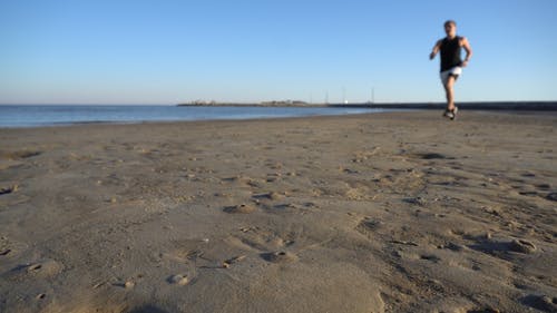 一个人在海滩海岸线上运行 · 免费素材视频