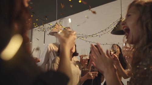 五彩纸屑倒下时，聚会中的人们举起眼镜扔 · 免费素材视频