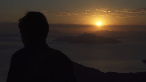 一个人在山顶上看着地平线上的日落美景 · 免费素材视频