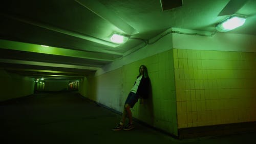 一名年轻女子倚在地下通道的墙上 · 免费素材视频