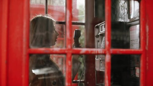 一个女人在电话亭内使用电话 · 免费素材视频