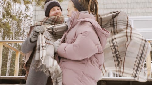 一对穿着全套冬季服装在寒冷的天气中拥抱外面的夫妇 · 免费素材视频