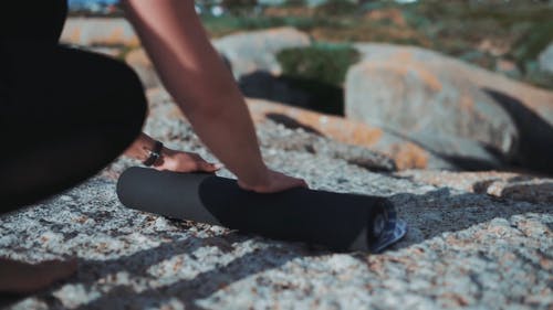 一个女人在平坦的岩层表面上铺瑜伽垫 · 免费素材视频