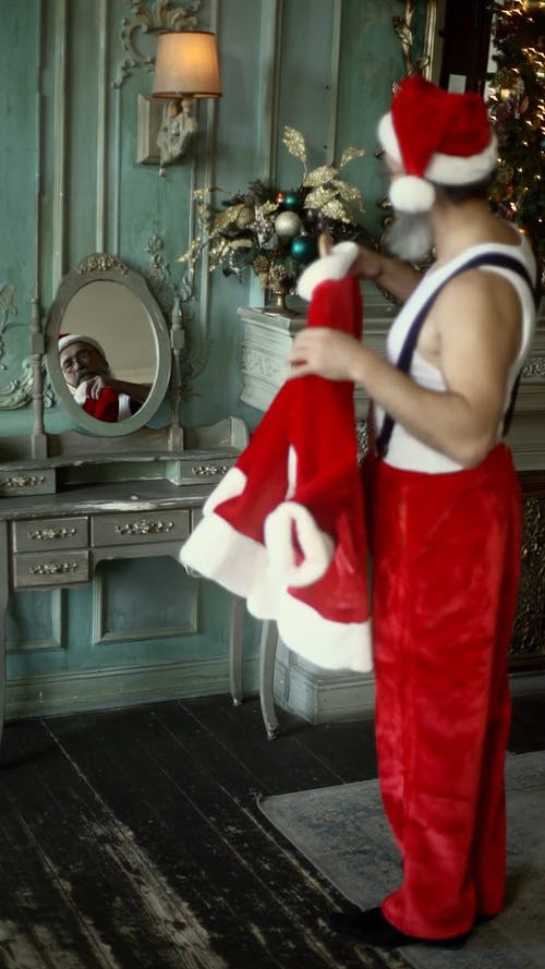 一个老人看着自己抱着圣诞老人服装的镜子 · 免费素材视频
