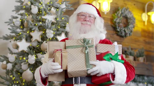 圣诞老人站在一棵圣诞树，拿着礼物盒 · 免费素材视频