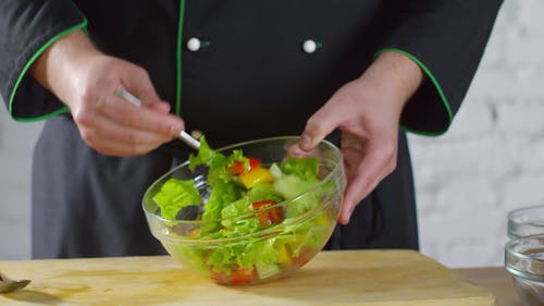 厨师把蔬菜沙拉放在碗里撒酱 · 免费素材视频