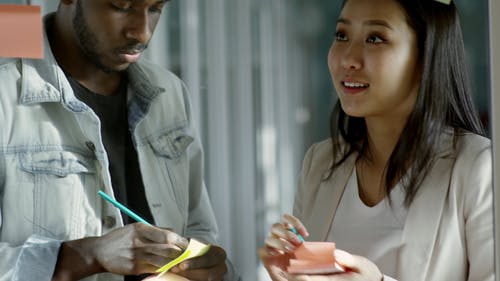 一个男人和一个女人在玻璃面板上贴一个便条纸 · 免费素材视频