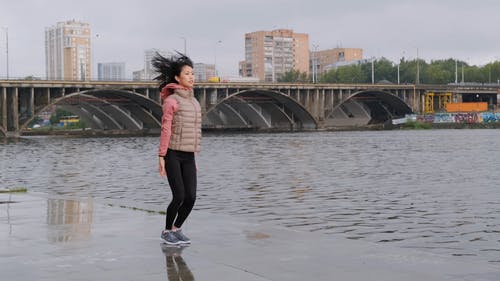 一个女人在河边做跳操 · 免费素材视频
