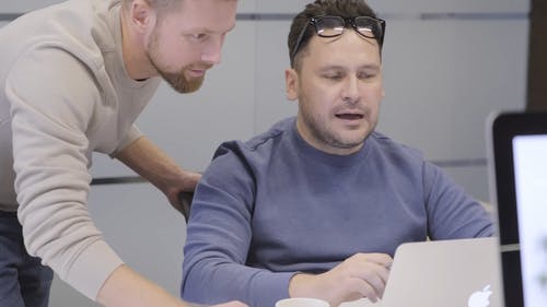 一名男子向他的同事讨论他在笔记本电脑上完成的工作 · 免费素材视频