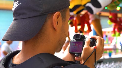 一位在游乐园里为玩具奖拍照的摄影师 · 免费素材视频