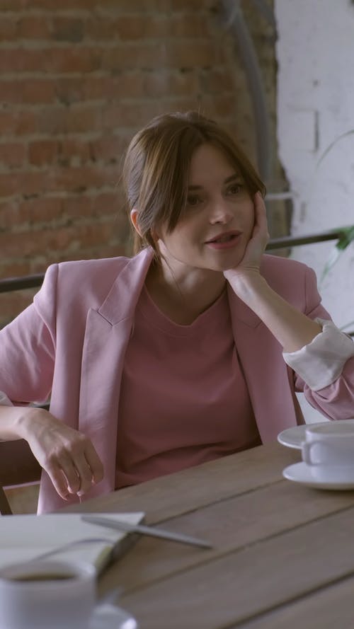 一个女人坐在一张木桌旁，在谈话中用餐 · 免费素材视频